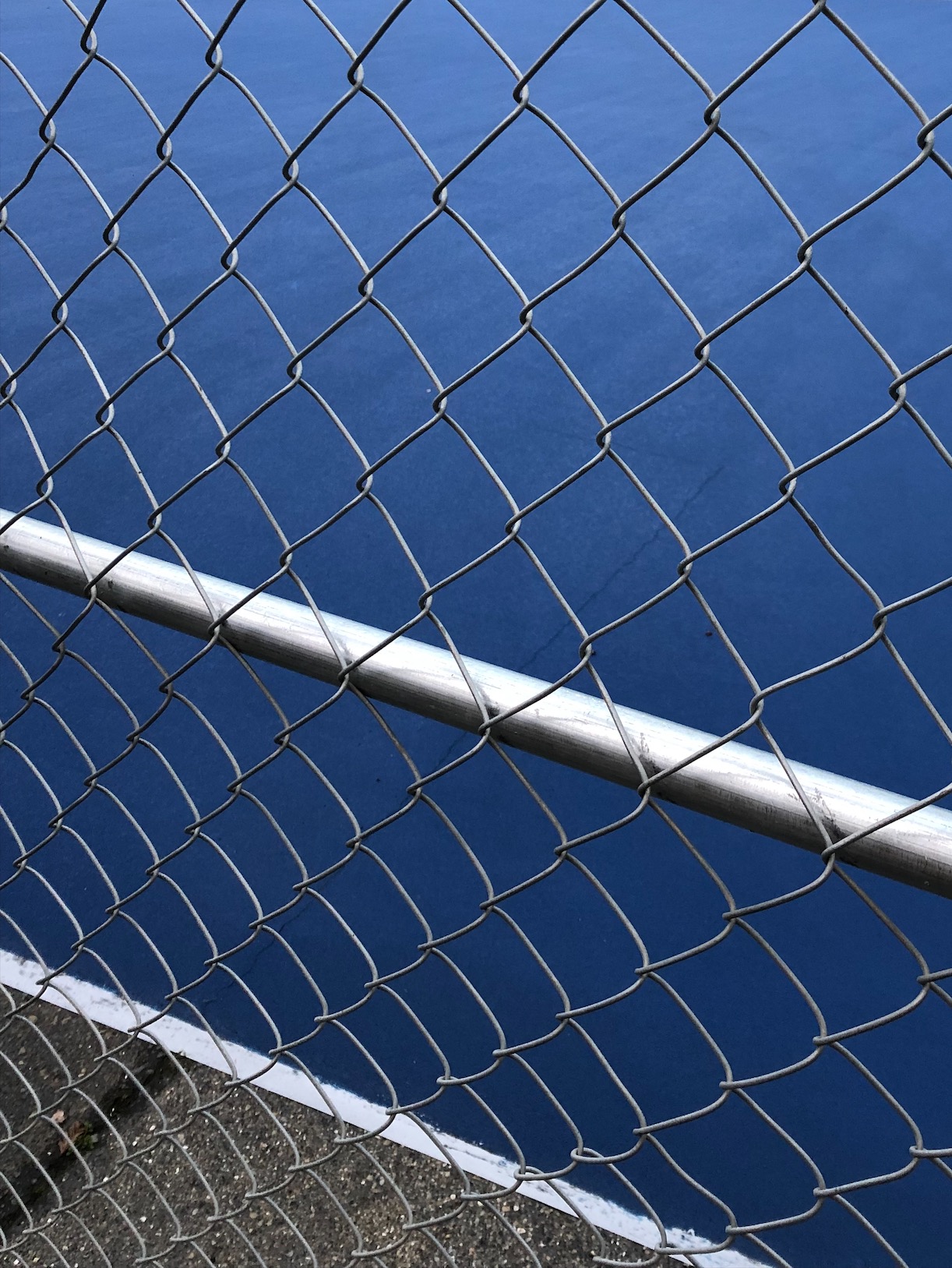 metal fence against blue basketball court
